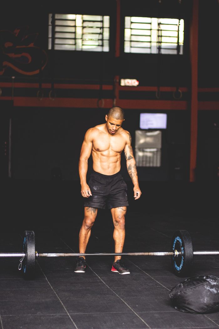 Elementor #1456 Muscular man shirtless preparing for a weightlifting workout in a gym setting.