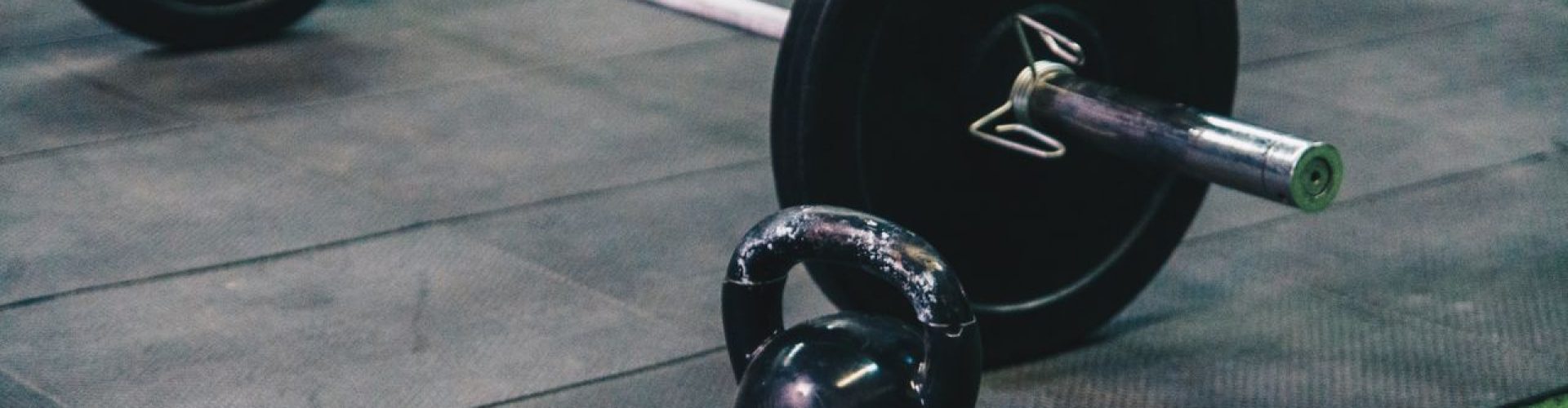 Barbell and kettlebell on gym floor, ideal for fitness and strength training themes.